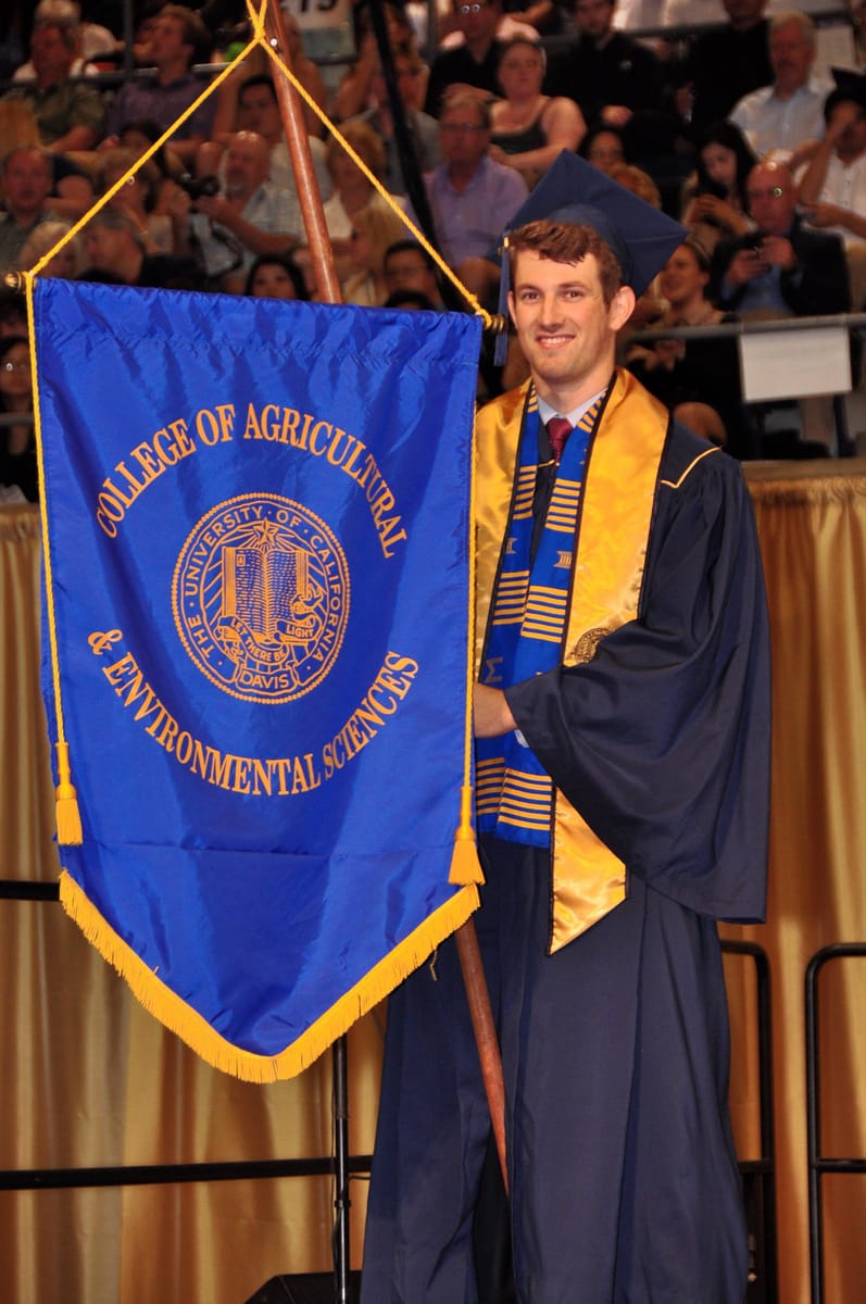 John carrying the UC Davis College of Agricultural & Environmental Sciences banner at commencement