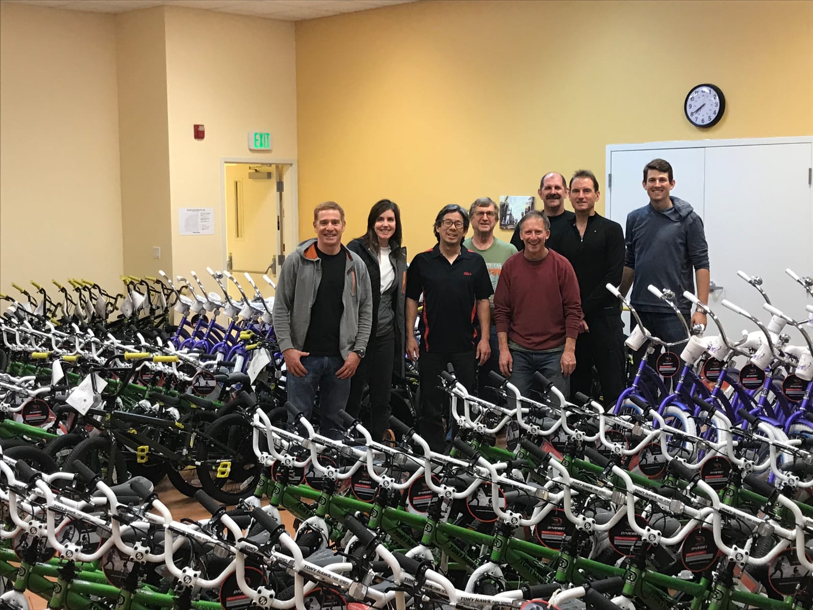 John and a team beside rows of new kids' bikes at a giveaway