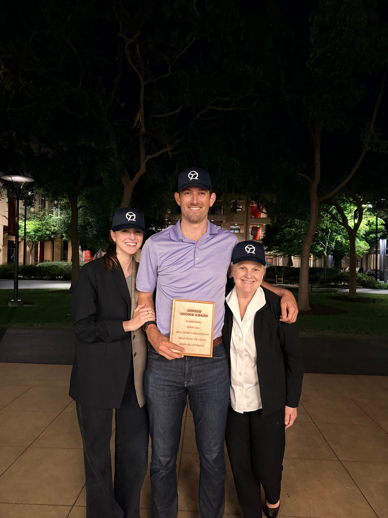 John holding the Judges' Choice Award plaque outside after the final presentations, in a QualityTime cap, with his mom beside him.