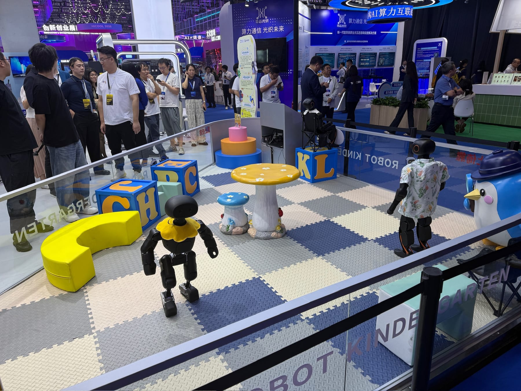 Small humanoid robots on a foam play mat inside an exhibit labeled Robot Kindergarten.